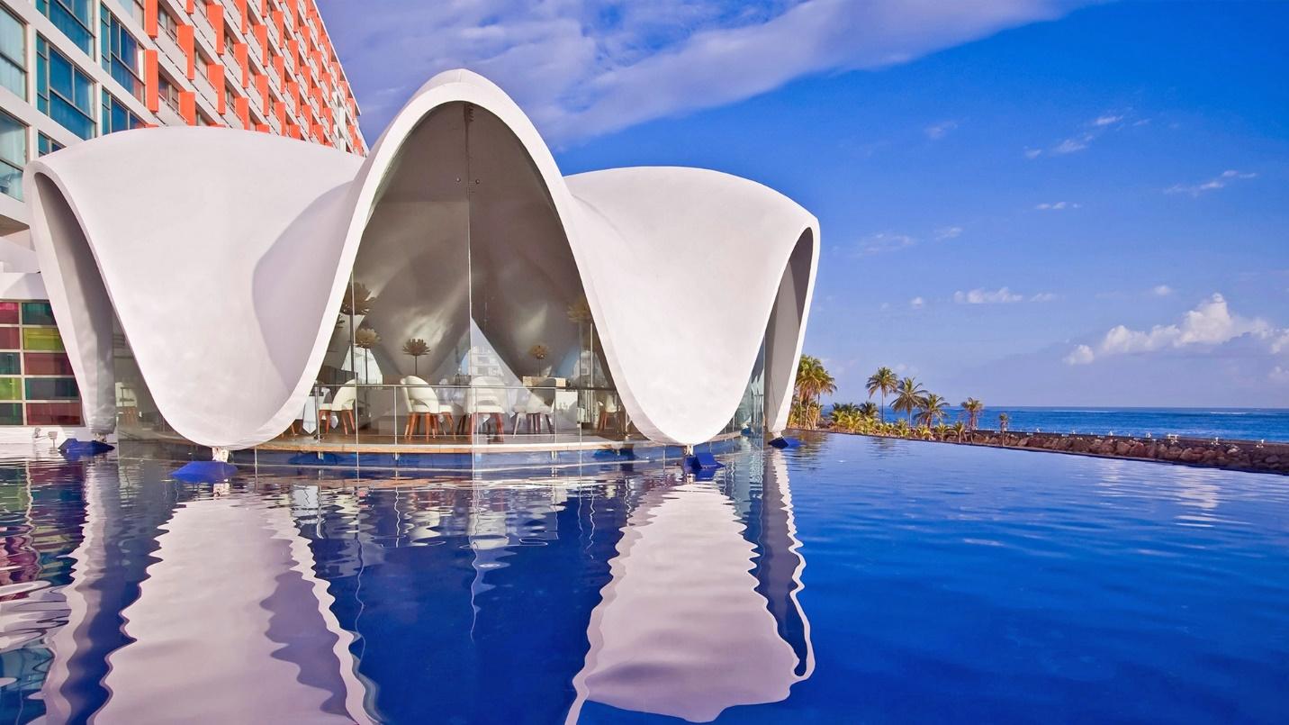 Perla, a seashell-shaped room with wavy white walls, by the water in a section about La Concha Renaissance San Juan Resort.