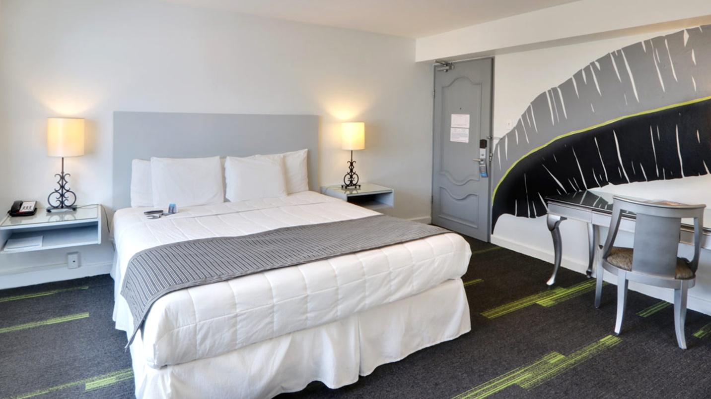 A standard King room with gray and white décor at Hotel Miramar in a section about the neighborhood’s hotels.