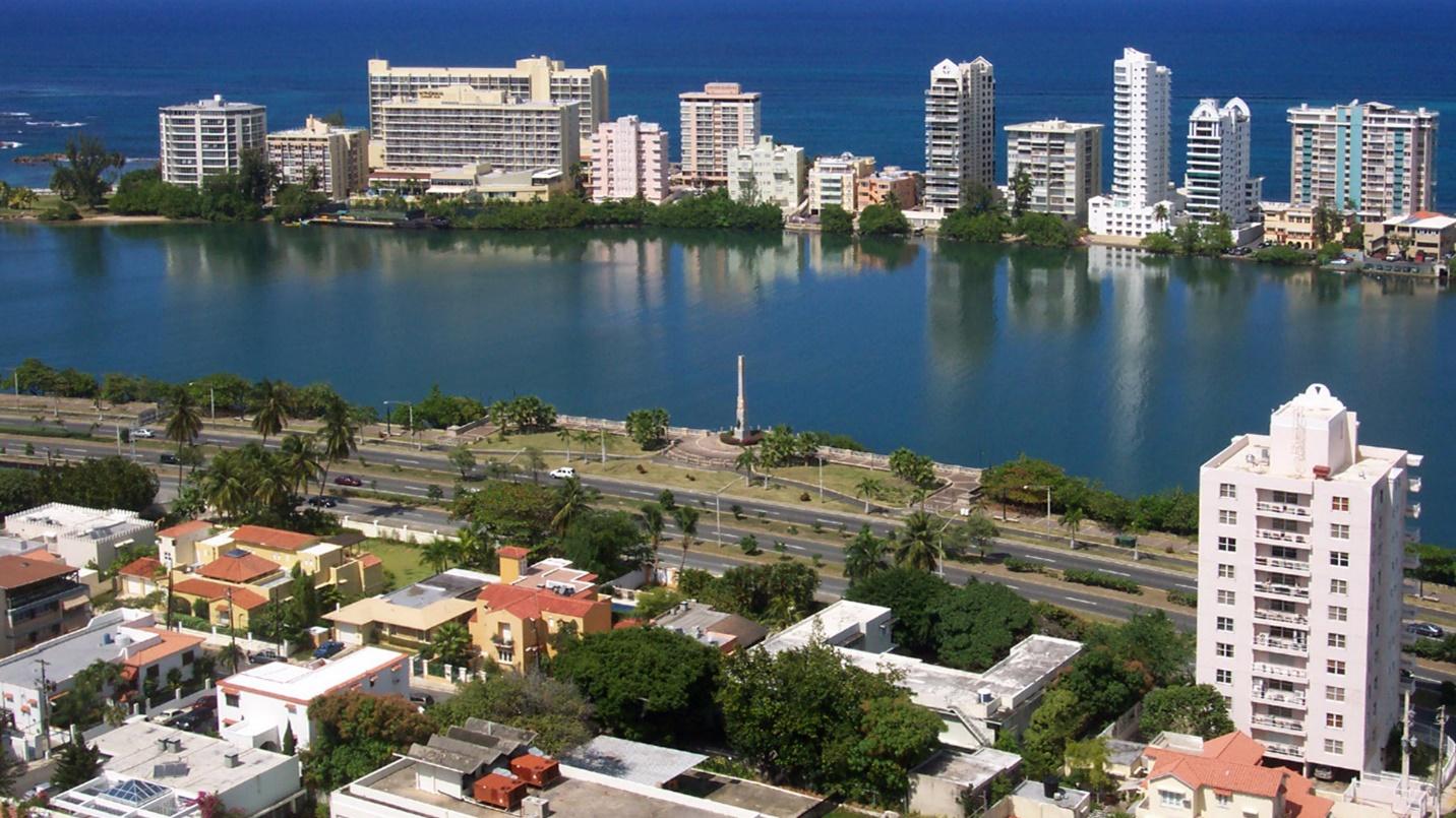 Waterfront high-rises and highways in a section introducing the location and population of Miramar, Puerto Rico.