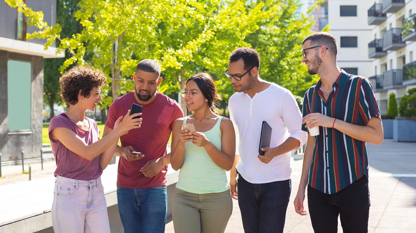 A diverse group of young adults walking and chatting outdoors in a modern Puerto Rican neighborhood, building friendships and community.